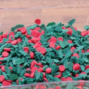 Peut inclure: Un récipient en plastique transparent rempli de vermicelles de Noël rouges et verts. Les vermicelles sont en forme de sapins de Noël, de feuilles de houx et de cercles.
