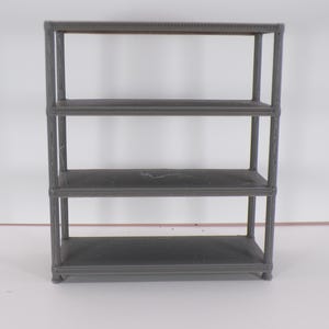 Może przedstawiać: Szara, trzypoziomowa półka. Półki są prostokątne i podparte pionowymi słupkami na każdym rogu. Jednostka wykonana jest z ciemnoszarego materiału i przeznaczona jest do przechowywania lub ekspozycji.