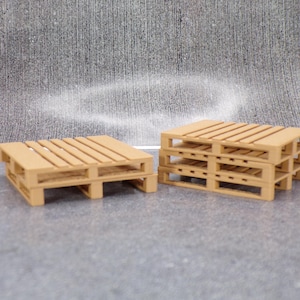 May include: Two wooden pallets, one stacked on top of the other, against a grey background. The top pallet is a single layer, while the bottom pallet is stacked three layers high.