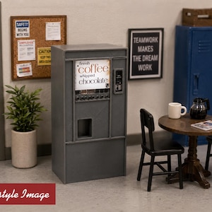 May include: A miniature gray vending machine featuring a display panel with the text fresh coffee whipped chocolate, a selection of buttons, and a dispensing slot. The unit is designed for a dollhouse setting, capturing the look of a breakroom.