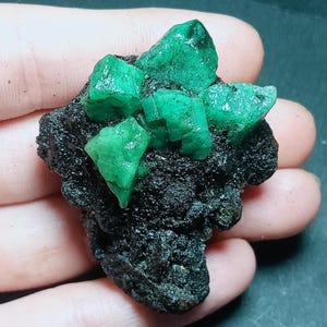 以下が含まれることがあります： 黒い持ち手と「But First, Coffee」のテキストが黒い太字で書かれた白いセラミックマグ。マグは白い表面に置かれています。マグは355 mlのようです。