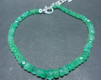 May include: A green emerald gemstone bracelet with a silver clasp. The bracelet is made of small, faceted emerald beads.