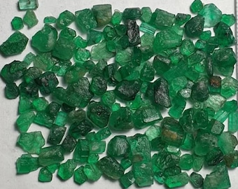Könnte beinhalten: Eine Sammlung roher Smaragd-Edelsteine in verschiedenen Formen und Größen. Die Smaragde zeigen eine Reihe von Grüntönen, von hell bis tief, mit sichtbaren natürlichen Texturen und Facetten. Die Edelsteine sind verstreut.