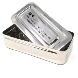 Puede incluir: Caja de recuerdo de acero inoxidable con un diseño de huella de pata y corazón. La tapa está grabada con el texto "My Heart will Always Wear the Footprints Left by You".