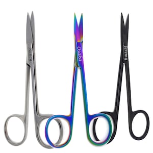 May include: Three pairs of small scissors with personalized names: Nancy, Osaka, and Jeremy. The scissors are silver, rainbow, and black.