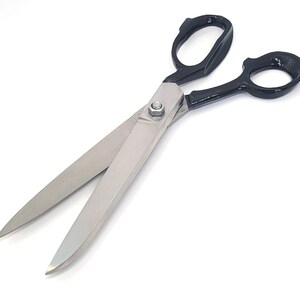 May include: A pair of large, black-handled scissors with silver blades. The scissors are open and the blades are sharp.