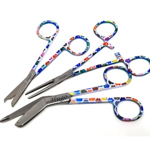 Peut inclure: Ensemble de cinq instruments chirurgicaux en acier inoxydable avec des poign&eacute;es &agrave; motifs floraux color&eacute;s. Chaque instrument porte le nom "Hugo" grav&eacute;. Les poign&eacute;es pr&eacute;sentent un m&eacute;lange de motifs floraux bleus, rouges, jaunes et verts.