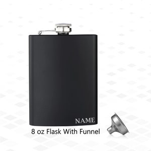 Puede incluir: Una petaca negra de 237 ml con tapón y embudo plateados. La petaca tiene la palabra "NAME" grabada en la parte delantera.