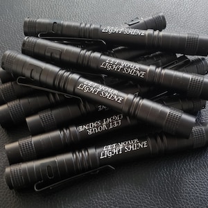May include: A stack of black metal flashlights with the inscription "Let Your Light Shine" engraved on each one.