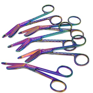 May include: A set of six rainbow-coloured surgical scissors with a textured finish. Each scissor has the word "Name" engraved on the handle.