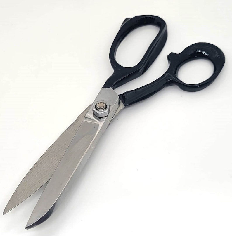 May include: Fabric shears with black handles and a silver blade. The shears have a metal screw in the centre.