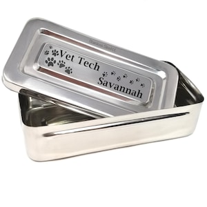 May include: Stainless steel rectangular box with a lid. The lid is engraved with the text "Vet Tech Savannah" and paw prints.