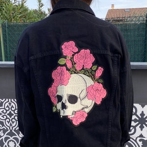 May include: Black denim jacket with a skull and pink roses embroidered on the back.