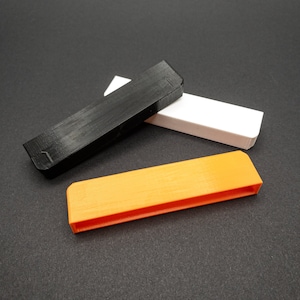 Może przedstawiać: Trzy prostokątne plastikowe pojemniki w kolorze czarnym, białym i pomarańczowym. Pojemniki są ułożone jeden na drugim.