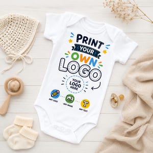 Puede incluir: Un body blanco de manga corta para bebé con el texto PRINT YOUR OWN LOGO en azul, verde y negro. Debajo, un círculo discontinuo contiene el texto YOUR LOGO HERE, con iconos de un lápiz, una imagen y la letra T, ANY LOGO, ANY IMAGE, ANY TEXT.