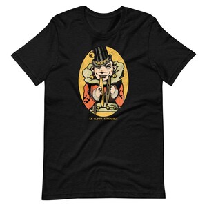 May include: Black t-shirt with a vintage illustration of a clown playing cymbals. The illustration is surrounded by a yellow oval with the text "Le Clown Extensible".