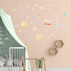 Könnte beinhalten: Eine Kinderzimmerwand, die mit farbenfrohen arabischen Alphabet- und Symbolaufklebern dekoriert ist. Die Aufkleber zeigen Sterne, Monde, Regenbogen und ein offenes Buch. Ein Kinderbett mit grünem Baldachin und eine Holzspielplatz sind im Vordergrund.