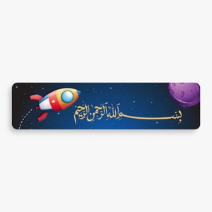 Op de afbeelding: Een blauwe en zwarte banner met een cartoon-raket die door de ruimte vliegt. De banner heeft een gouden Arabische inscriptie die "Bismillah Al-Rahman Al-Rahim" luidt en een paarse planeet in de rechterbovenhoek.
