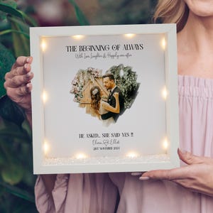 May include: White light-up frame with a photo of a couple in a heart-shaped cutout. The text reads "The Beginning of Always with Love, Laughter & Happily ever after" and "He asked... She said yes!!! Oliman & Elliat 21st November 2021".