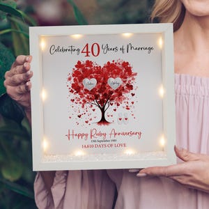 May include: A white framed anniversary art piece with a red heart-shaped tree design. The text reads "Celebrating 40 Years of Marriage" and "Happy Ruby Anniversary". Includes the names "Adam" and "Ashley" on the heart.