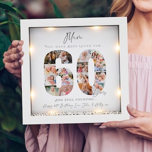 May include: A white framed photo collage with the word "Mum" at the top. The number "60" is formed by multiple photos. Text reads "You have been loved for... and still counting... Happy 60th Birthday Love John & Holly".