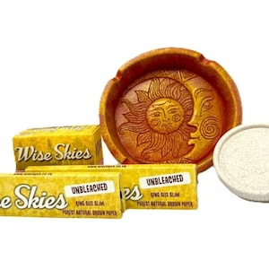 May include: A set of unbleached rolling papers with the brand name "Wise Skies" printed on the packaging. The papers are king size slim and made from natural brown paper. The set also includes a ceramic ashtray with a sun and moon design and a white ceramic coaster.