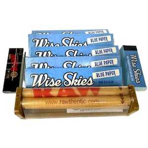 Könnte beinhalten: Eine Auswahl an Raucherzubehör, darunter blaue und weiße Wise Skies Zigarettenpapier, eine Raw-Rollmaschine und eine Packung Raw-Filtertips. Die Wise Skies Papiere sind mit "Blue Paper" und "King Size Slim" beschriftet.