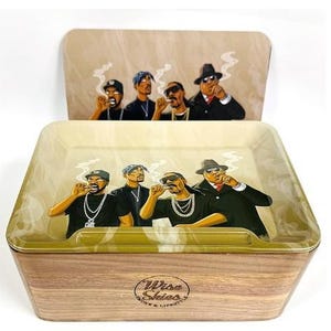 May include: A wooden rolling tray with a lid, featuring an illustration of four figures smoking. The tray has a light brown wood grain base and a cream-coloured interior. The lid displays the same illustration. The tray is labelled "Wise Skies".