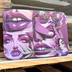 May include: Rectangular purple rolling tray with a collage of illustrations. The artwork features close-ups of women's faces, lips, and sunglasses, with cannabis leaf and smoking imagery. The tray is made of metal.
