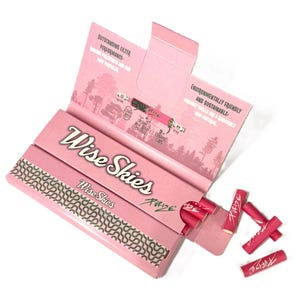 May include: Pink box of Wise Skies rolling papers with a pack of Purize filters. The box features a forest scene and the text "Environmentally Friendly and Sustainable".