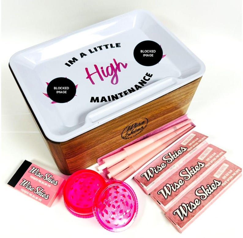 Puede incluir: Una bandeja de rodadura de madera con una tapa blanca que dice "Soy un poco de alto mantenimiento". La bandeja tiene un peque&ntilde;o compartimento para papeles de fumar y un molinillo. Tambi&eacute;n hay papeles de fumar rosas y molinillos rosas en la imagen.