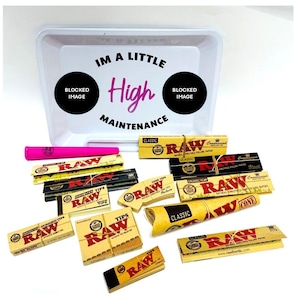 May include: A white rolling tray with the text "I'm a little high maintenance" printed on it. The tray is filled with various RAW rolling papers, cones, and tips. The papers are brown and have the RAW logo printed on them.
