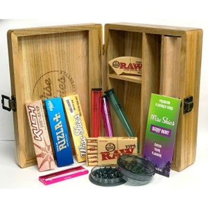 May include: Wooden box with a variety of smoking accessories, including rolling papers, tips, a grinder, and a small pouch. The box is labeled "Wise Skies Lifestyle".
