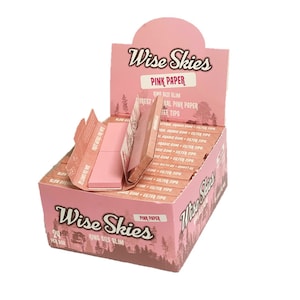 Può includere: Una scatola di cartine da sigaretta Wise Skies rosa con 24 cartine slim di formato king per scatola. La scatola è rosa con una scena di foresta e il testo "Wise Skies" e "Pink Paper".