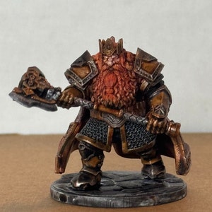 May include: A painted miniature figurine of a dwarf king wearing a crown and armor, holding a large axe. The dwarf has a long red beard and is standing on a round base.