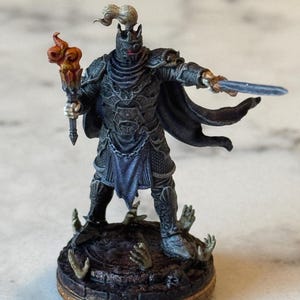 May include: A painted miniature figure of a knight in black armor holding a flaming torch and a sword. The knight stands on a circular base with sculpted hands reaching up from the ground.