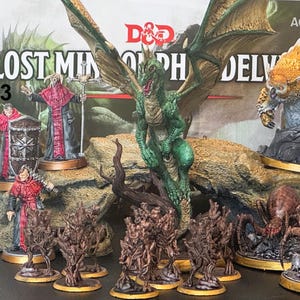May include: A collection of Dungeons & Dragons miniatures, including a green dragon, spiders, and figures in red robes. The backdrop features the text "LOST MINES OF PHANDELVER" and "AGE 12+". The words "Chapter 3 Part 2" are also visible.