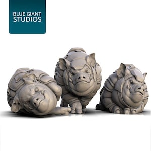 May include: Three gray, stylized rhino-pig hybrid figurines. The figurines are in different poses, with one lying on its side. The text "BLUE GIANT STUDIOS" is in a teal box in the upper left corner.