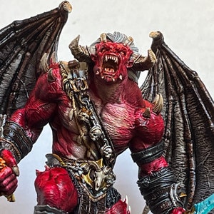 May include: A red demon figurine with horns, wings, and a chain. The demon is painted with a detailed, realistic style and has a fierce expression.