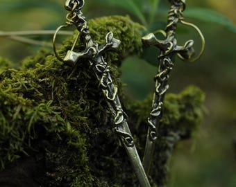 Pendientes largos de latón con forma de espada, decorados con motivos de plantas y hadas del bosque.