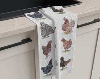 May include: A white kitchen towel featuring a colourful illustration of eight chickens. The chickens are depicted in various poses and colours, including black, brown, and grey.