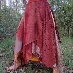 Op de afbeelding: Een meerlagige rok met een mix van stoffen in tinten bruin, rood en goud. De rok heeft een vloeiende, asymmetrische vorm en is perfect voor een bohemian of festival look.