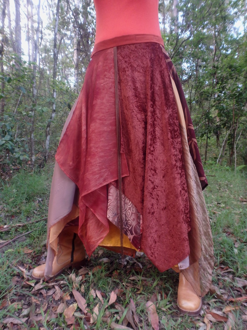 Op de afbeelding: Een meerlagige rok met een mix van stoffen in tinten bruin, rood en goud. De rok heeft een vloeiende, asymmetrische vorm en is perfect voor een bohemian of festival look.