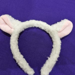 May include: White headband with fluffy white ears and pink inside the ears. The headband is made of soft, fuzzy material.