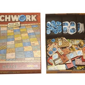 Puede incluir: Se muestra el juego de mesa "Patchwork", con la caja abierta para revelar las piezas del juego. La tapa de la caja presenta el título del juego y un diseño de patchwork. En el interior, las piezas del juego están organizadas en compartimentos, incluyendo botones azules y parches de tela.