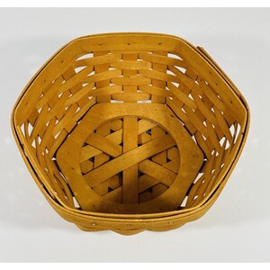May include: A woven basket with a hexagonal shape and a natural wood finish. The basket has a woven pattern and a solid bottom.