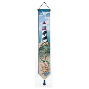 May include: A tapestry wall hanging depicting a lighthouse with a red roof and black and white stripes, against a blue ocean backdrop. The lighthouse is surrounded by seashells and a starfish on a sandy beach. A seagull flies overhead.