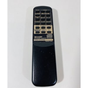 May include: Black remote control with buttons for CD, tuner, volume, power, tape, random, clear, memory, repeat, stop, play, preset, and pause. The remote has the text "SHARP INFRARED REMOTE CONTROL AUDIO SYSTEM RCONT1749A" and "COMPACT DISC DIGITAL AUDIO".