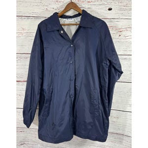 Può includere: Una giacca blu navy a maniche lunghe con chiusura a bottoni e un'etichetta Blair. La giacca ha una vestibilità rilassata e due tasche sul davanti.