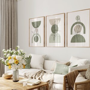 May include: Three framed abstract art prints with a minimalist design featuring green and beige geometric shapes and line drawings of leaves.